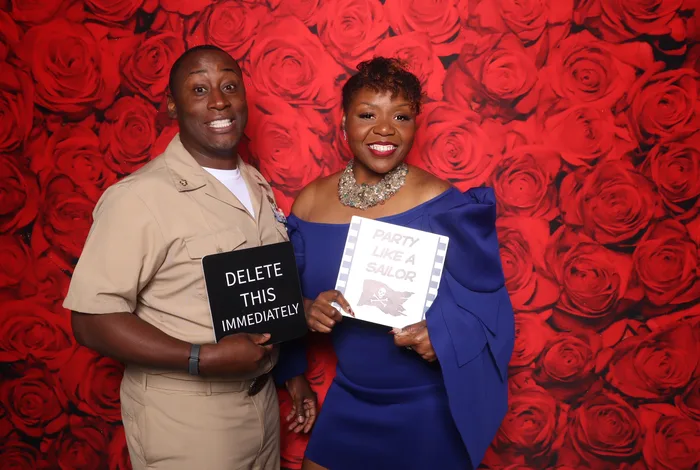 Navy couple with funny prop signs at Khaki Ball photo booth Hampton Roads 2026