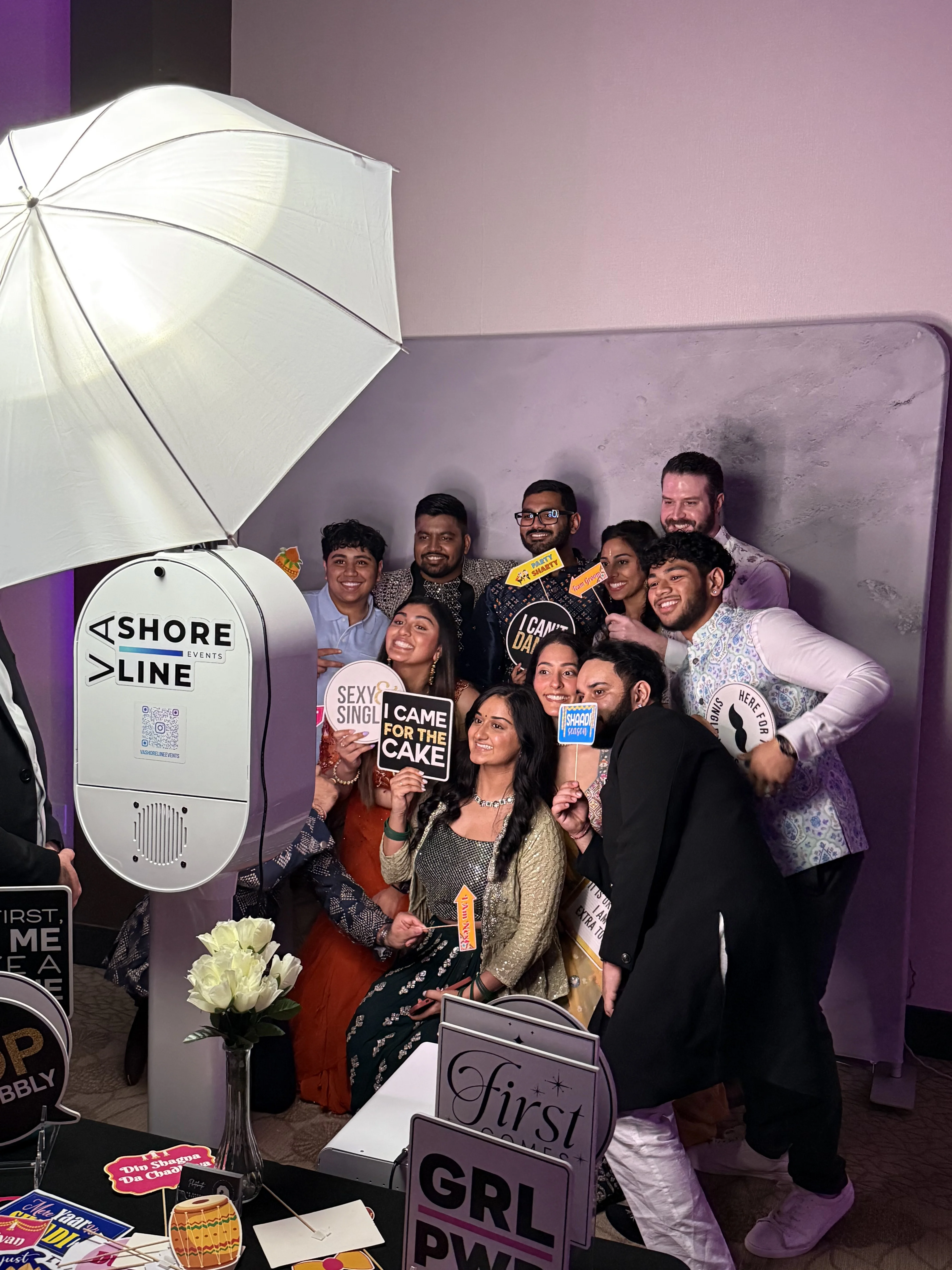 Indian wedding group photo booth Virginia Beach 2025 — large group of guests with fun props at reception