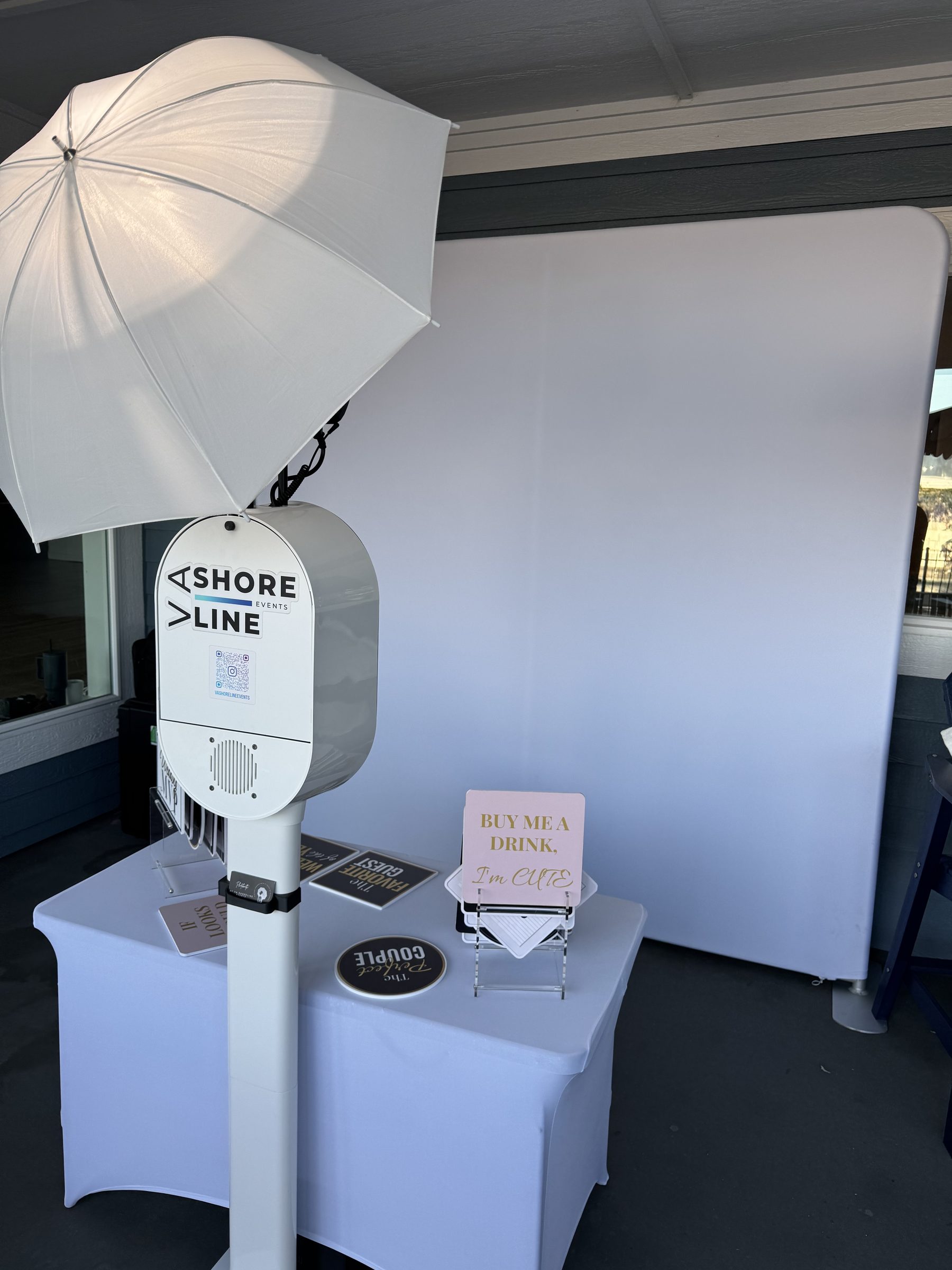 Outdoor photo booth setup at Virginia Beach wedding — Shore Line booth with white backdrop and props table