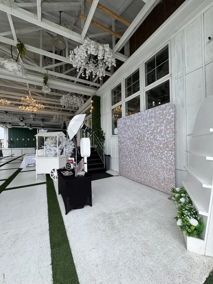 VA Shoreline Events photo booth setup with champagne glitter backdrop, studio umbrella light and props table, ready for guests inside an elegant Virginia Beach venue