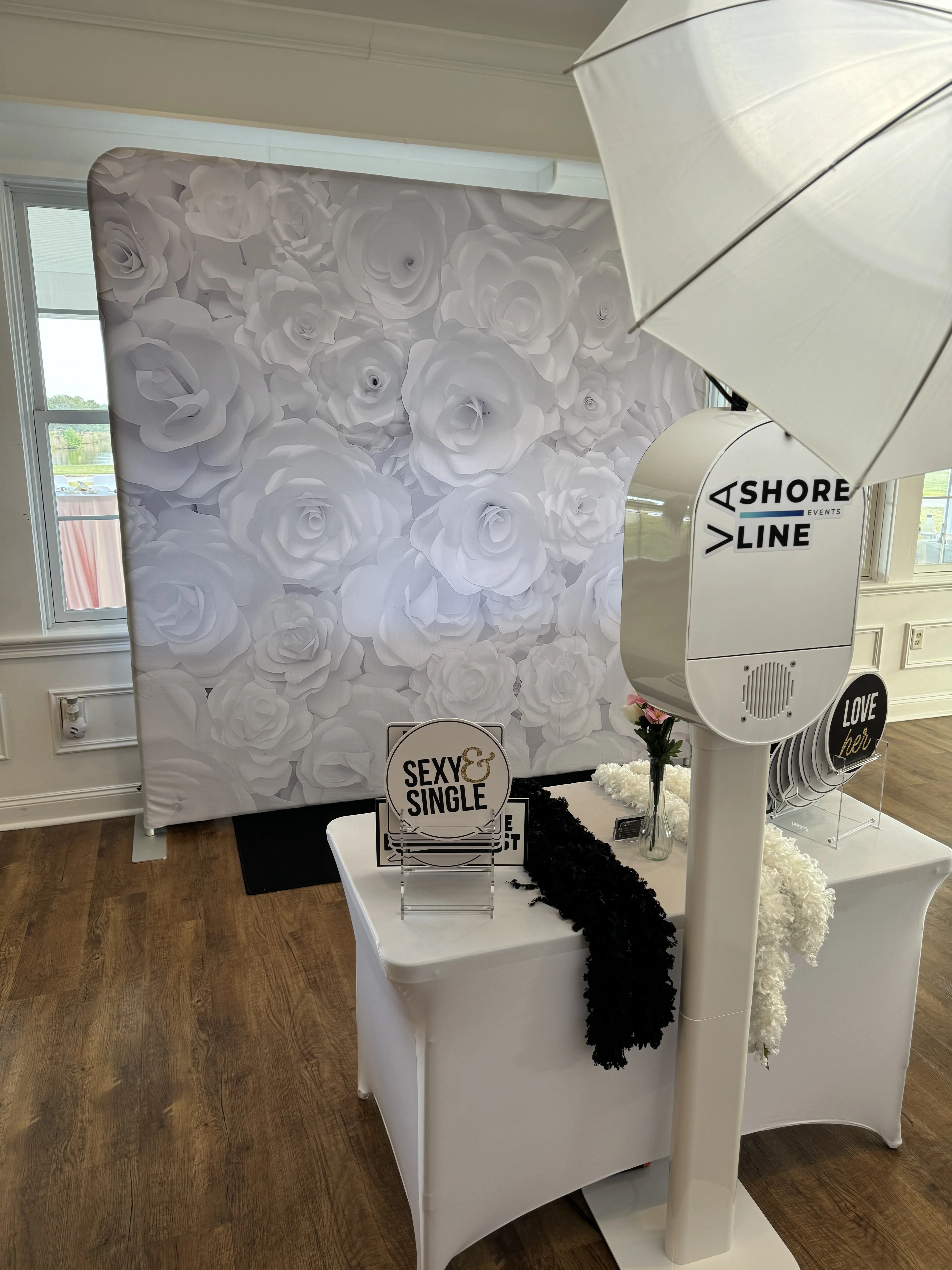 Photo booth white rose floral backdrop wedding setup Virginia Beach — props table with LOVE sign styled for reception