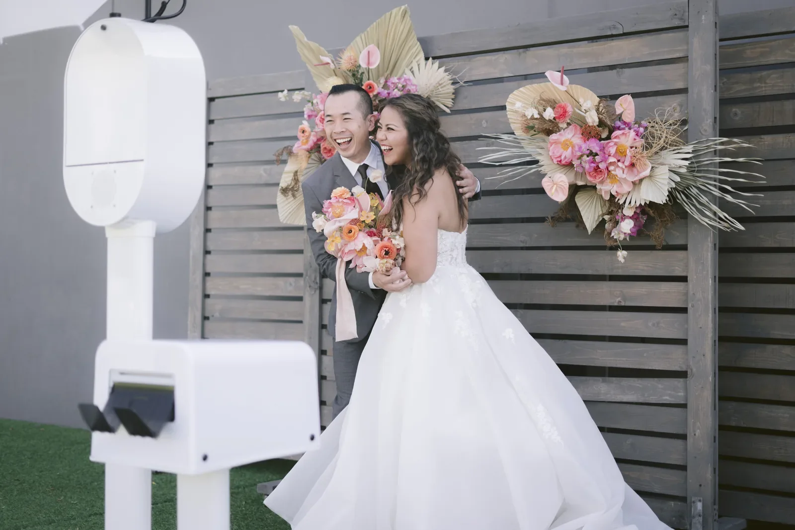 Wedding couple at outdoor floral backdrop photo booth